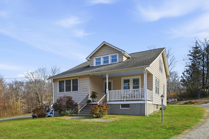 Bungalow-style home featuring a front lawn, covered porch, and a shingled roof