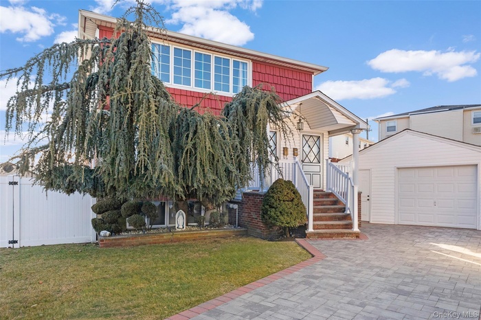 View of front of house featuring a garage, a front yard, decorative driveway, and an outdoor structure