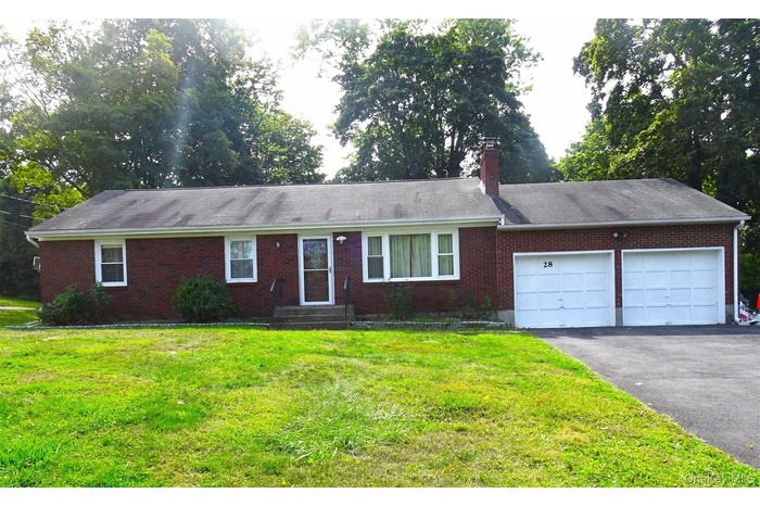 Ranch-style house with a garage, brick siding, a front yard, driveway, and a chimney