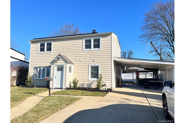 View of front of house featuring a carport, a chimney, driveway, and a front yard