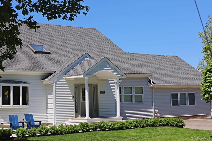 View of front of home featuring a front yard and a shingled roof