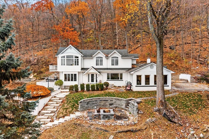 View of front of property with an outdoor fire pit surrounded by nature