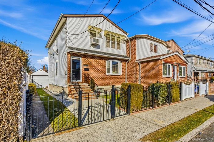 View of front facade featuring a fenced front yard, brick siding, a gate, and a garage
