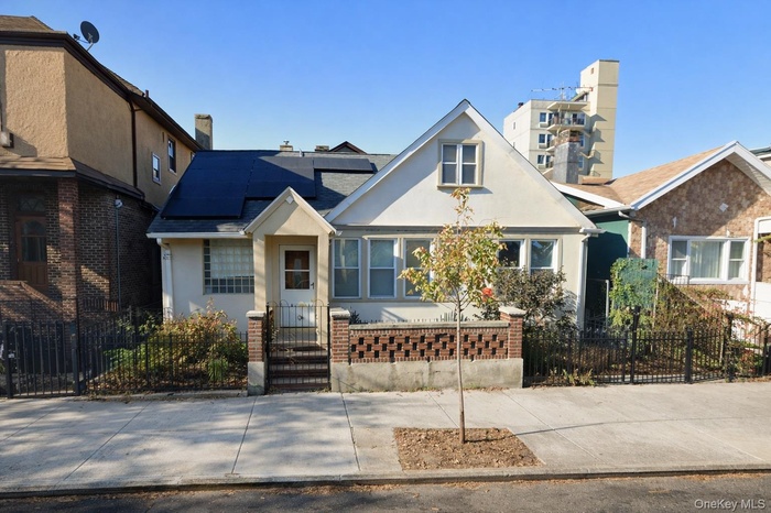 View of front of home featuring a fenced front yard, solar panels, stucco siding, and brick siding