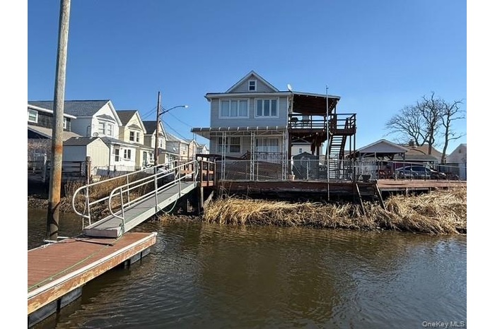 Back of house featuring a residential view, stairs, and a deck with water view