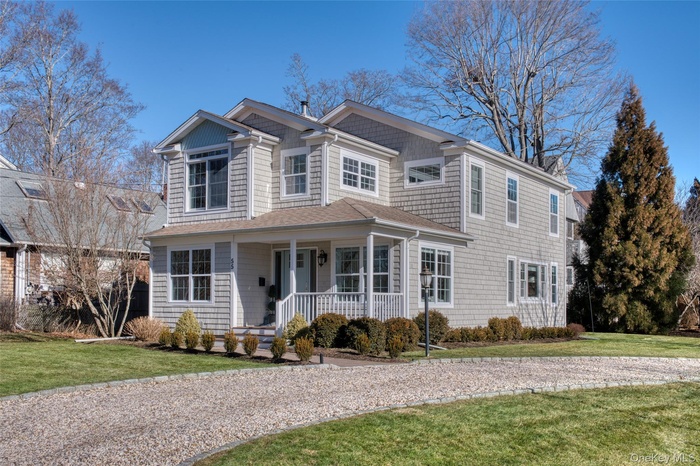 Shingle-style home with a front lawn and covered porch