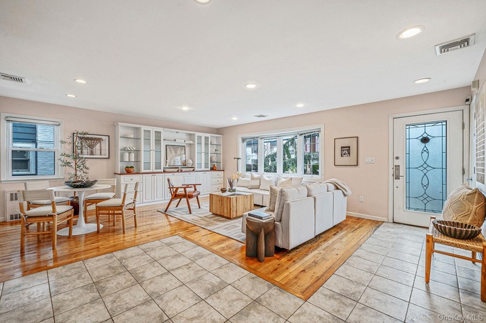 Living room with light tile patterned flooring, radiator, and recessed lighting