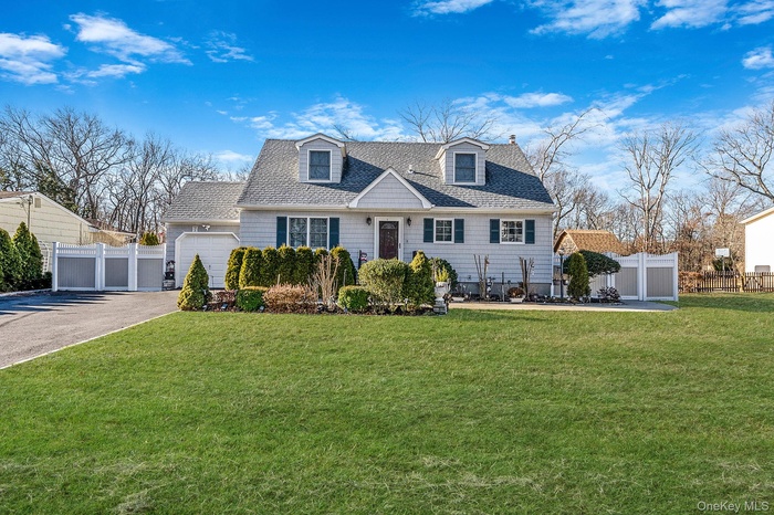 Cape cod home featuring roof with shingles, asphalt driveway, an attached garage, and a patio
