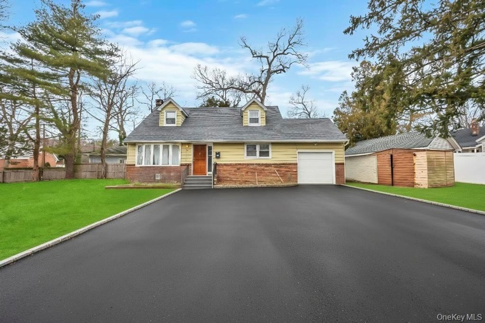 Cape cod house with brick siding, asphalt driveway, entry steps, and a chimney
