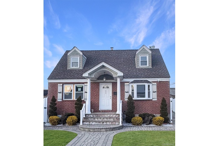 Cape cod house featuring brick siding, roof with shingles, and a front lawn