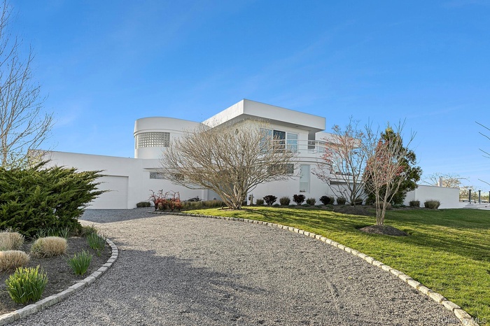 View of front of home with driveway, stucco siding, a front yard, and a garage