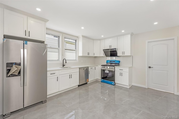 Kitchen featuring appliances with stainless steel finishes, white cabinets, under cabinet range hood, and recessed lighting