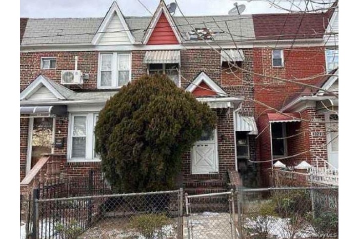 Traditional-style home with a gate, a fenced front yard, brick siding, and roof with shingles