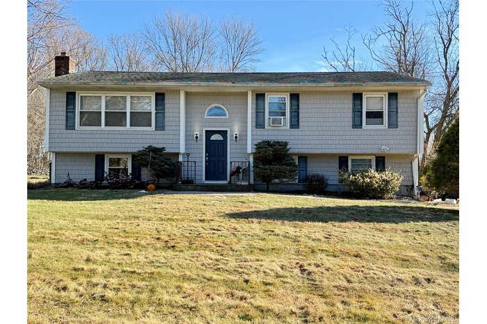 Bi-level home featuring a front lawn and a chimney