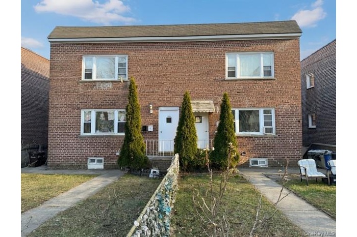 Traditional-style house with brick siding and a front lawn