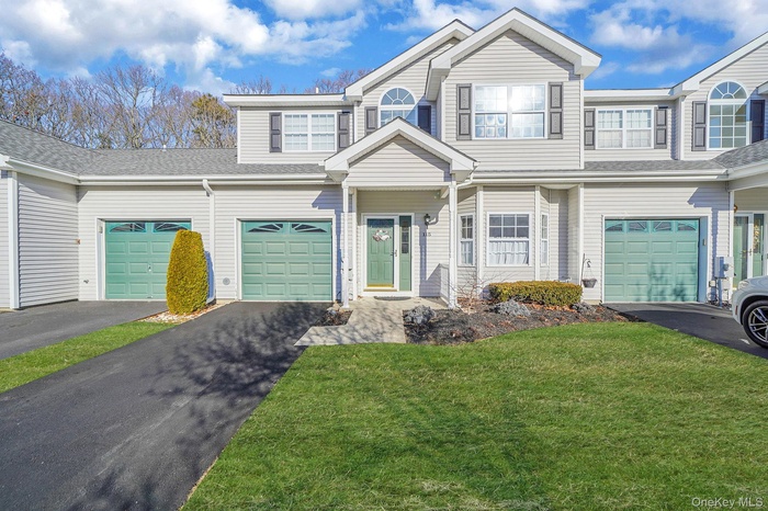 Traditional-style house featuring driveway, a front lawn, a garage, and roof with shingles