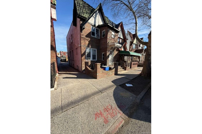 Back of house featuring brick siding and a tiled roof