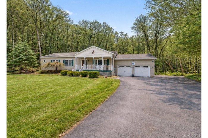 View of front of home featuring a porch, asphalt driveway, a front yard, and an attached garage