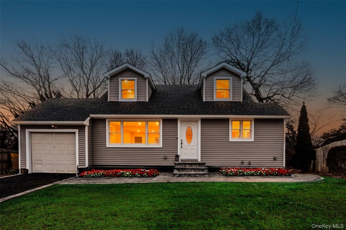 New england style home featuring a front lawn, a garage, entry steps, and asphalt driveway