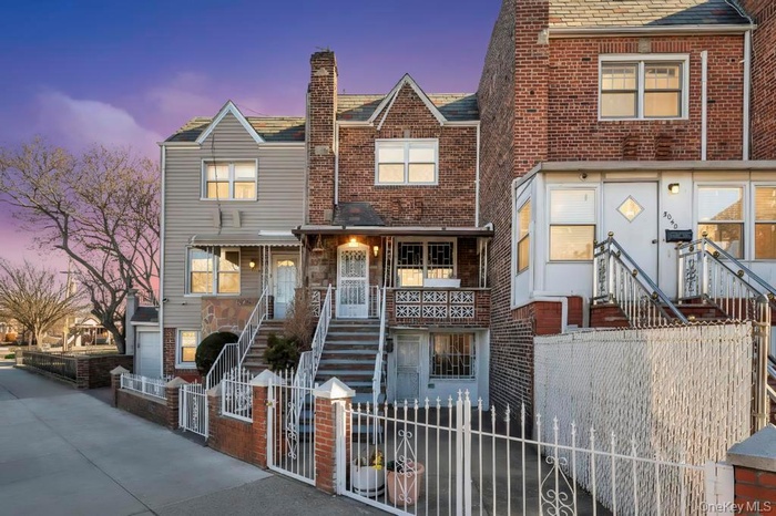 Traditional home featuring a gate, a fenced front yard, brick siding, and stairway
