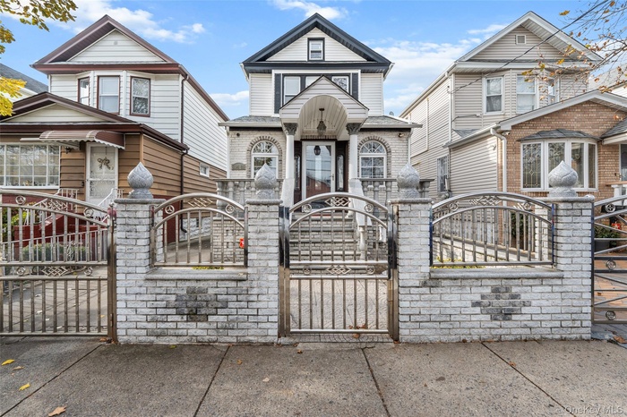 Victorian house with a gate, a fenced front yard, and brick siding