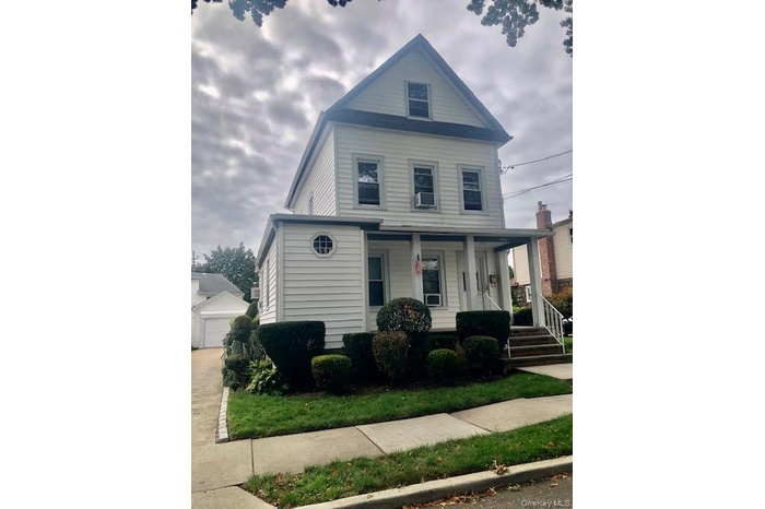View of front of house featuring covered porch and an outbuilding