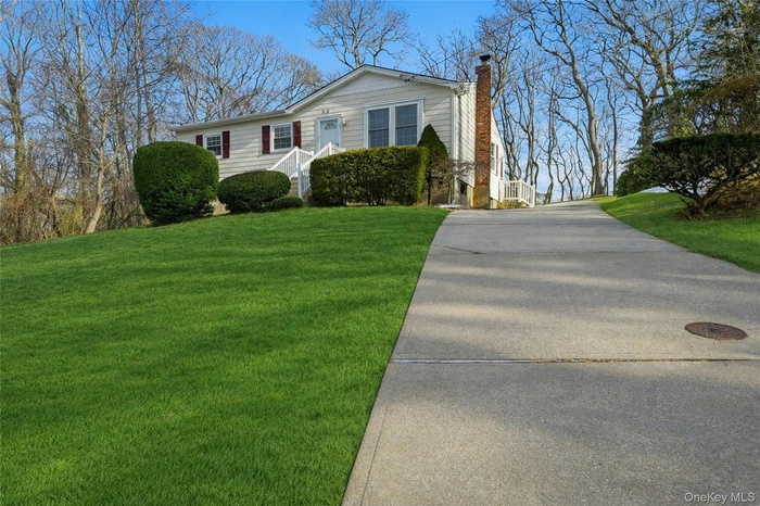 Grass was photographically enhanced.  View of front of home featuring a front yard, a chimney, and concrete driveway