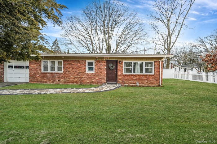 View of front of home with brick siding, a garage, and driveway