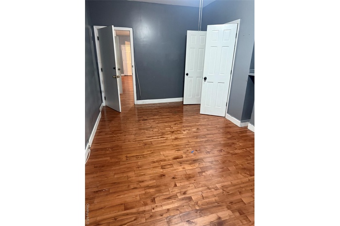 Unfurnished bedroom with hardwood / wood-style flooring and baseboards