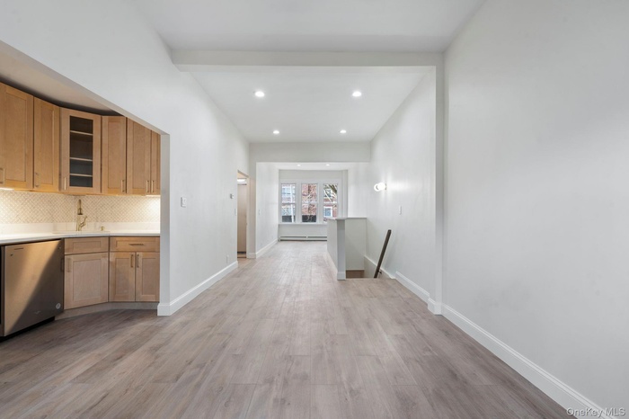 Hallway with an upstairs landing, light wood finished floors, recessed lighting, and a baseboard heating unit