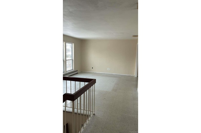 Empty room with light flooring and baseboard heating