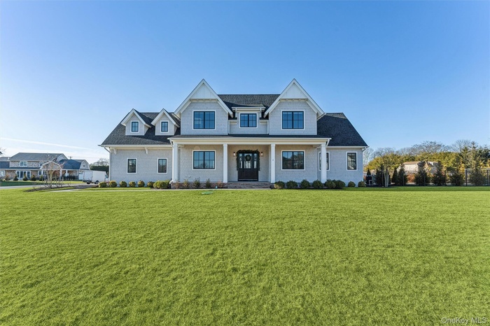 View of front of home with covered porch, a front lawn, and roof with shingles