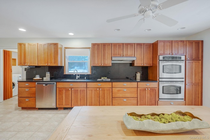 Kitchen featuring brown cabinets, stainless steel appliances, recessed lighting, decorative backsplash, and a ceiling fan