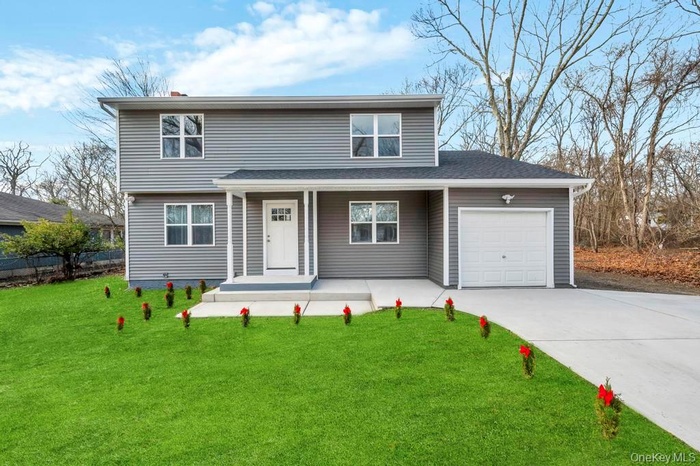 Traditional-style home featuring a porch, a garage, concrete driveway, a front yard, and a shingled roof