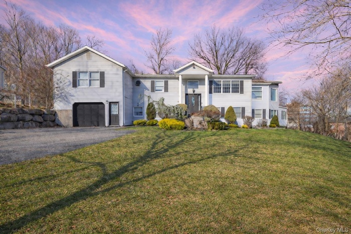 Raised ranch with driveway, a front lawn, and a garage