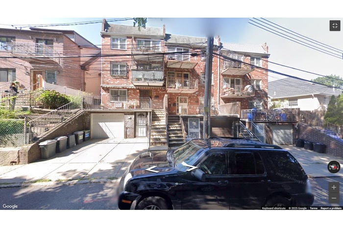 View of building exterior with stairs, a garage, and driveway