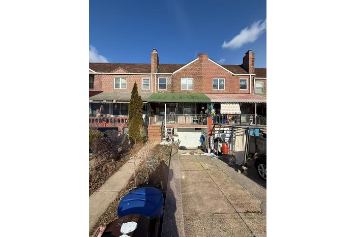 View of front of property with a chimney, brick siding, concrete driveway, an attached garage, and stairs