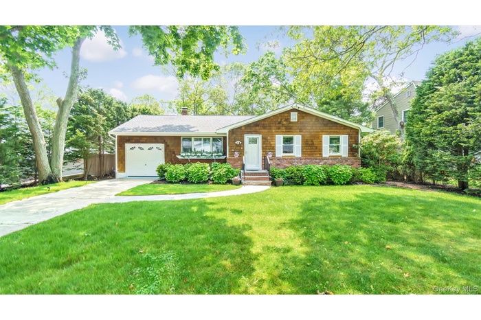 View of front of property with a front lawn, a garage, a chimney, and driveway