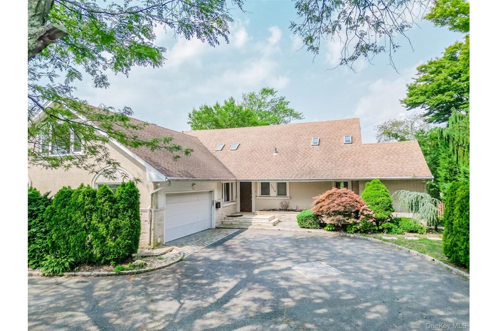 Ranch-style house featuring driveway, a garage, roof with shingles, and stucco siding