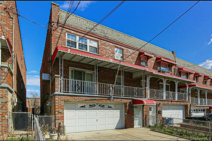 Traditional-style home featuring brick siding, mansard roof, concrete driveway, a garage, and a gate