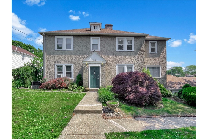 View of front of home featuring a front yard, stucco siding, and a chimney