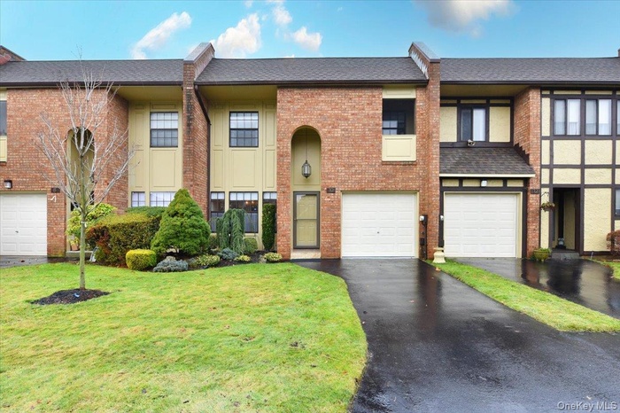 Split foyer home featuring a shingled roof, driveway, brick siding, a garage, and a front yard
