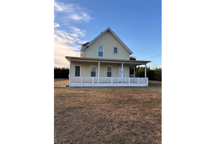 Farmhouse-style home with a front lawn and covered porch