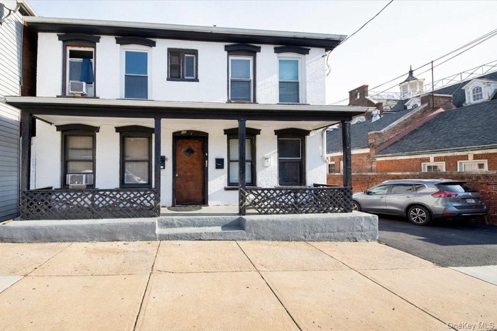 View of front of house featuring covered porch and brick siding