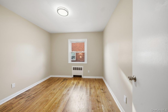 Spare room featuring radiator and light wood-type flooring