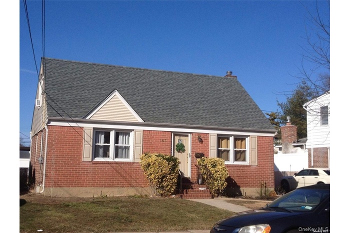 Cape cod home with brick siding, roof with shingles, and a front yard