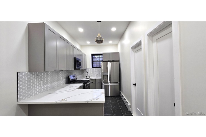 Kitchen featuring gray cabinetry, appliances with stainless steel finishes, a baseboard heating unit, tasteful backsplash, and decorative light fixtur