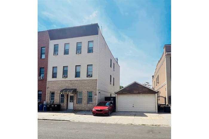 View of front of home with stone siding, an outdoor structure, and a detached garage