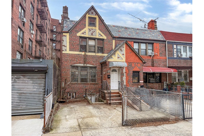 Tudor-style house featuring a chimney, a high end roof, brick siding, and a gate