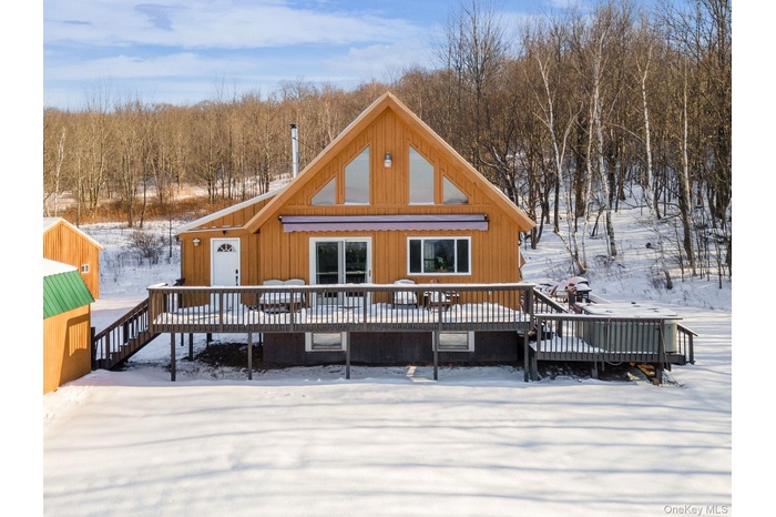 Snow covered house featuring a wooden deck